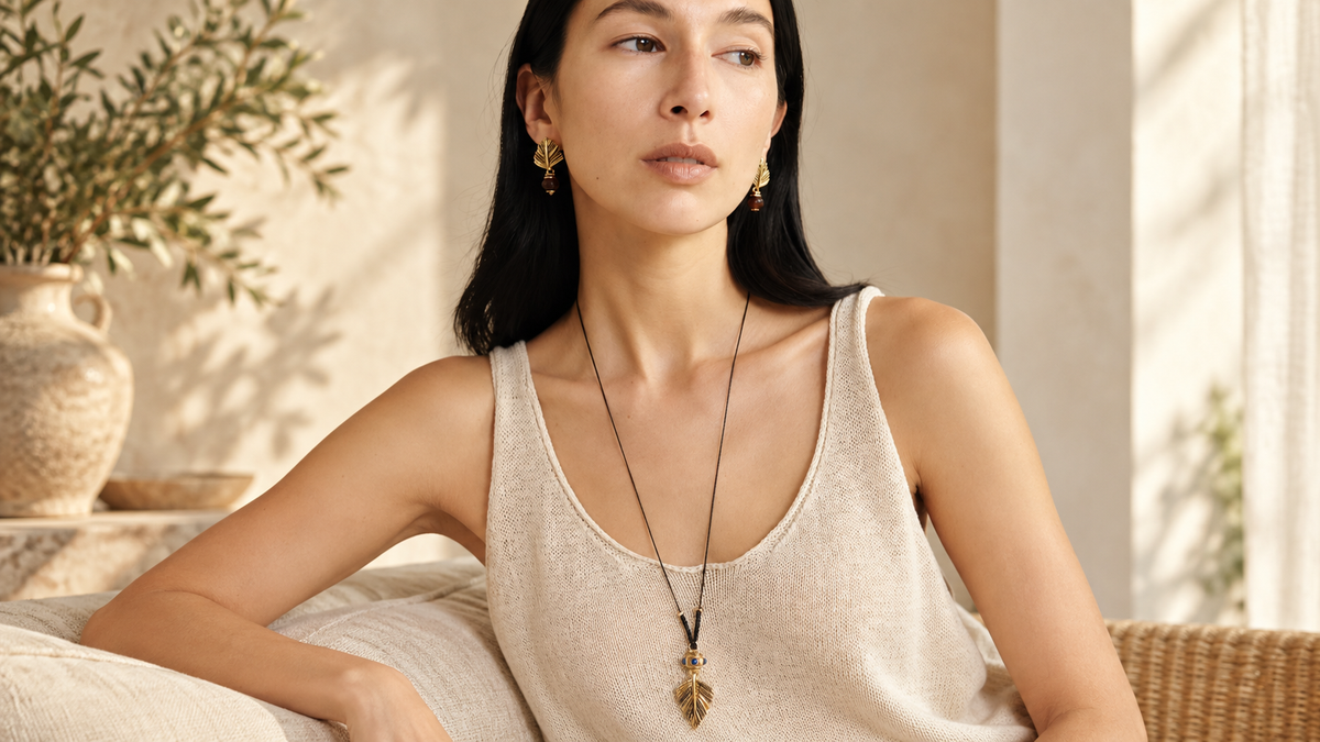 Woman wearing a gold-tone tassel cord pendant necklace with a cream knit top in warm natural light