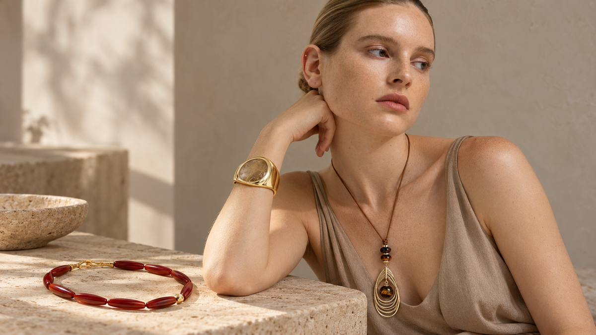 Model wearing a tiger eye pendant necklace with red agate and smoky quartz jewelry styled in a natural light editorial setting.