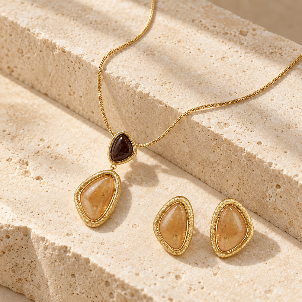Bound Light collection image featuring a sculptural pendant necklace and matching stud earrings on warm stone steps