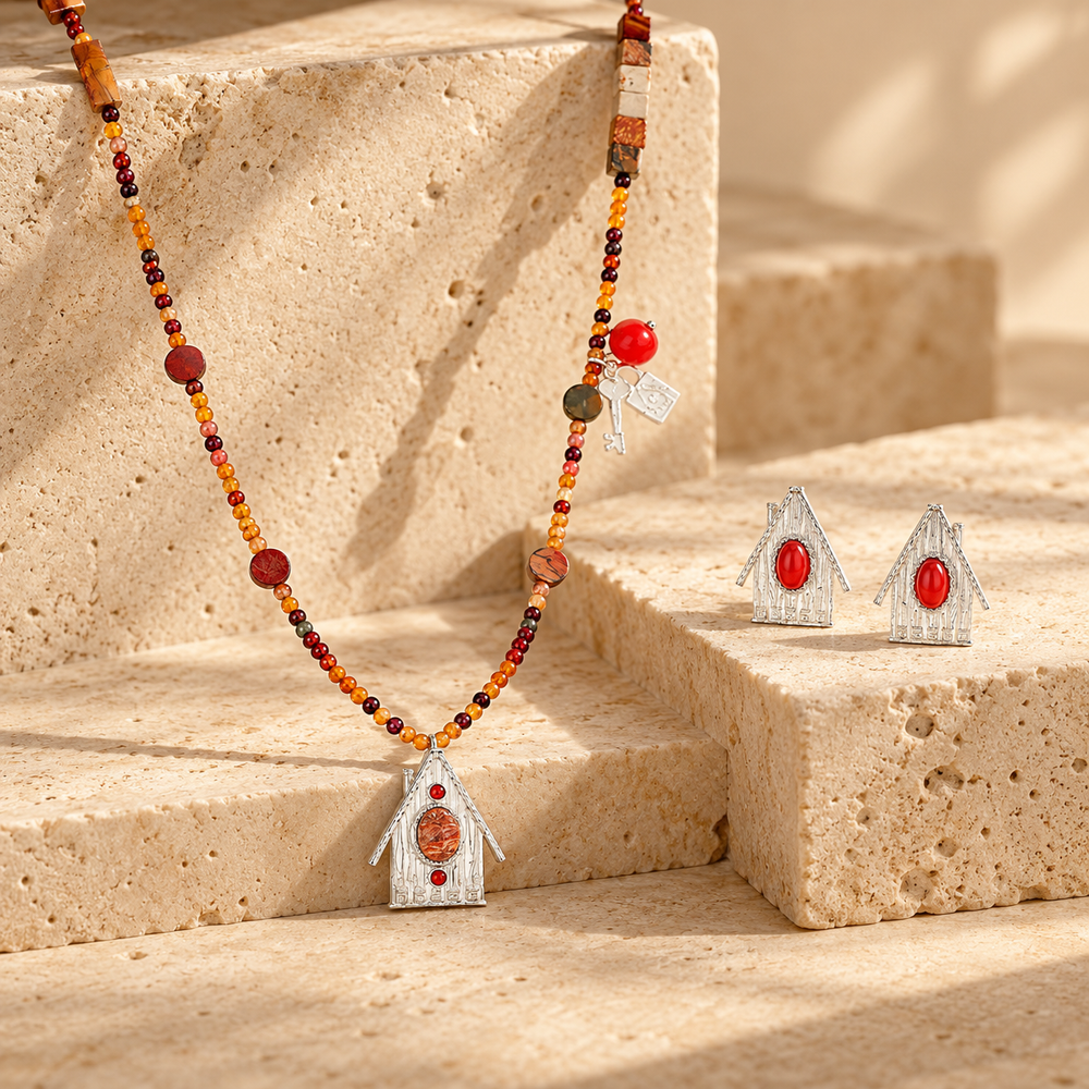 House Charm collection image featuring a beaded necklace and matching house-shaped earrings on warm stone steps