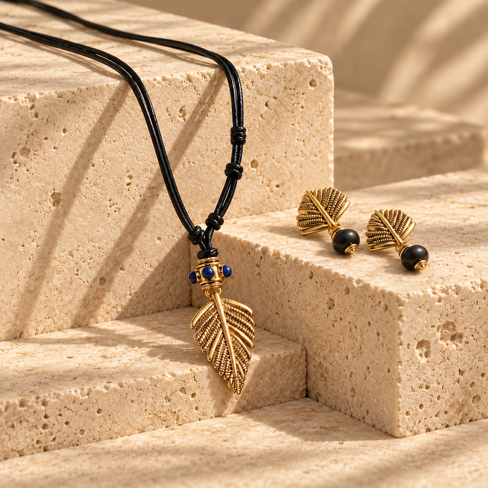 Swaying Palm gold-tone botanical pendant necklace with lapis lazuli accents and coordinating agate stud earrings on warm stone blocks