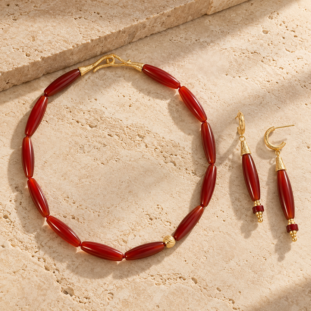 Vessel Agate collection image featuring a red agate collar necklace and matching drop earrings on warm stone steps