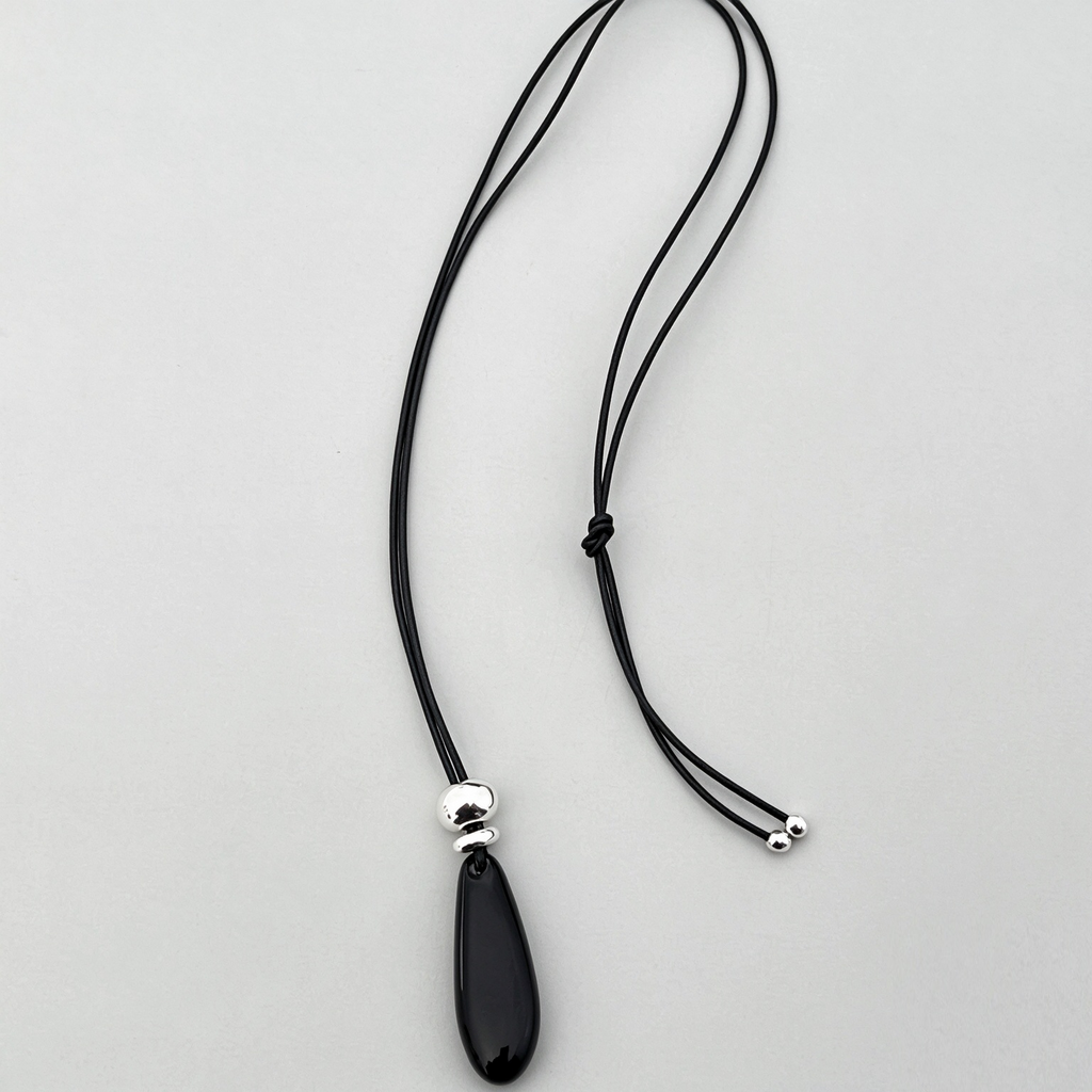 Polished black onyx teardrop pendant with silver-tone metal accent