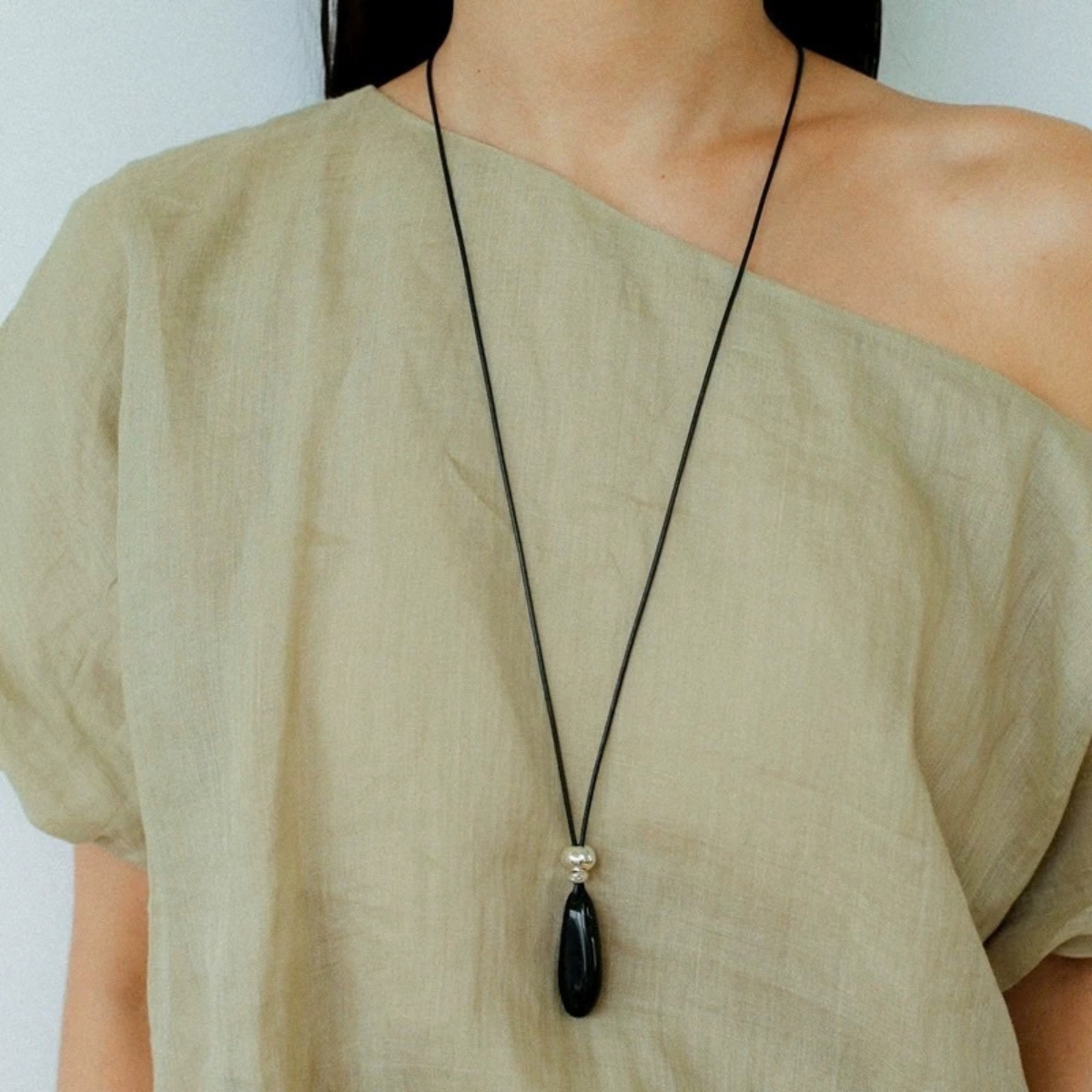 Long black onyx teardrop necklace worn with a minimal black cord