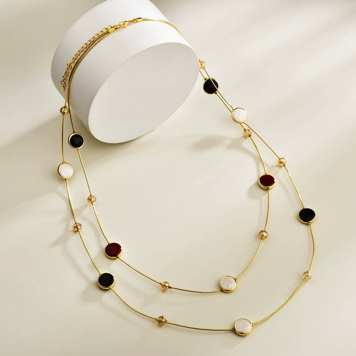 Black and red layered long necklace with gold-tone chains and crystal bead accents