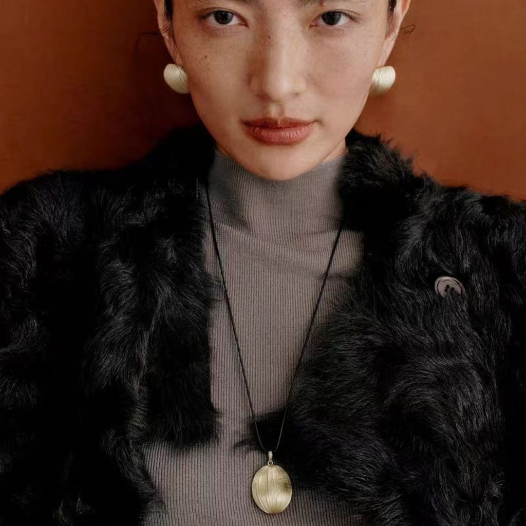 Model wearing the Gold-Tone Bound Light brushed necklace and sculptural stud earrings