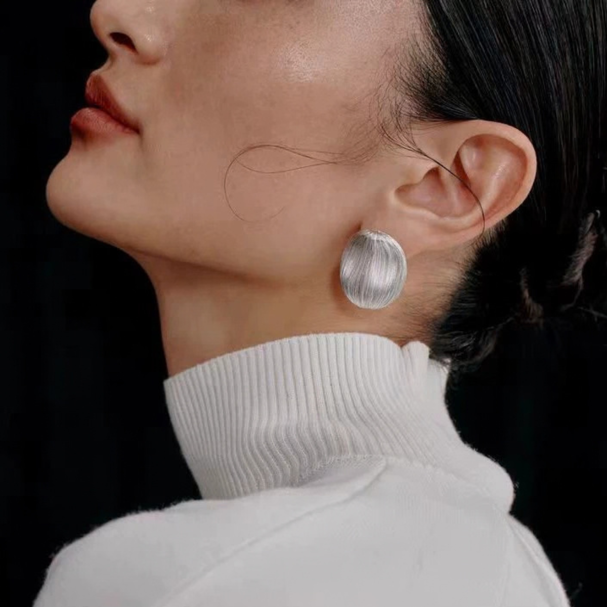 Model wearing Bound Light brushed sculptural stud earrings in Large Silver-Tone