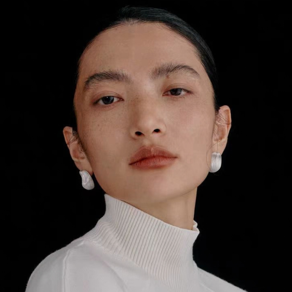 Model wearing Bound Light brushed sculptural stud earrings in Small Silver-Tone