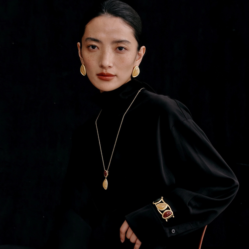 Model wearing the Gold-Tone Bound Light long necklace, earrings and cuff three-piece set