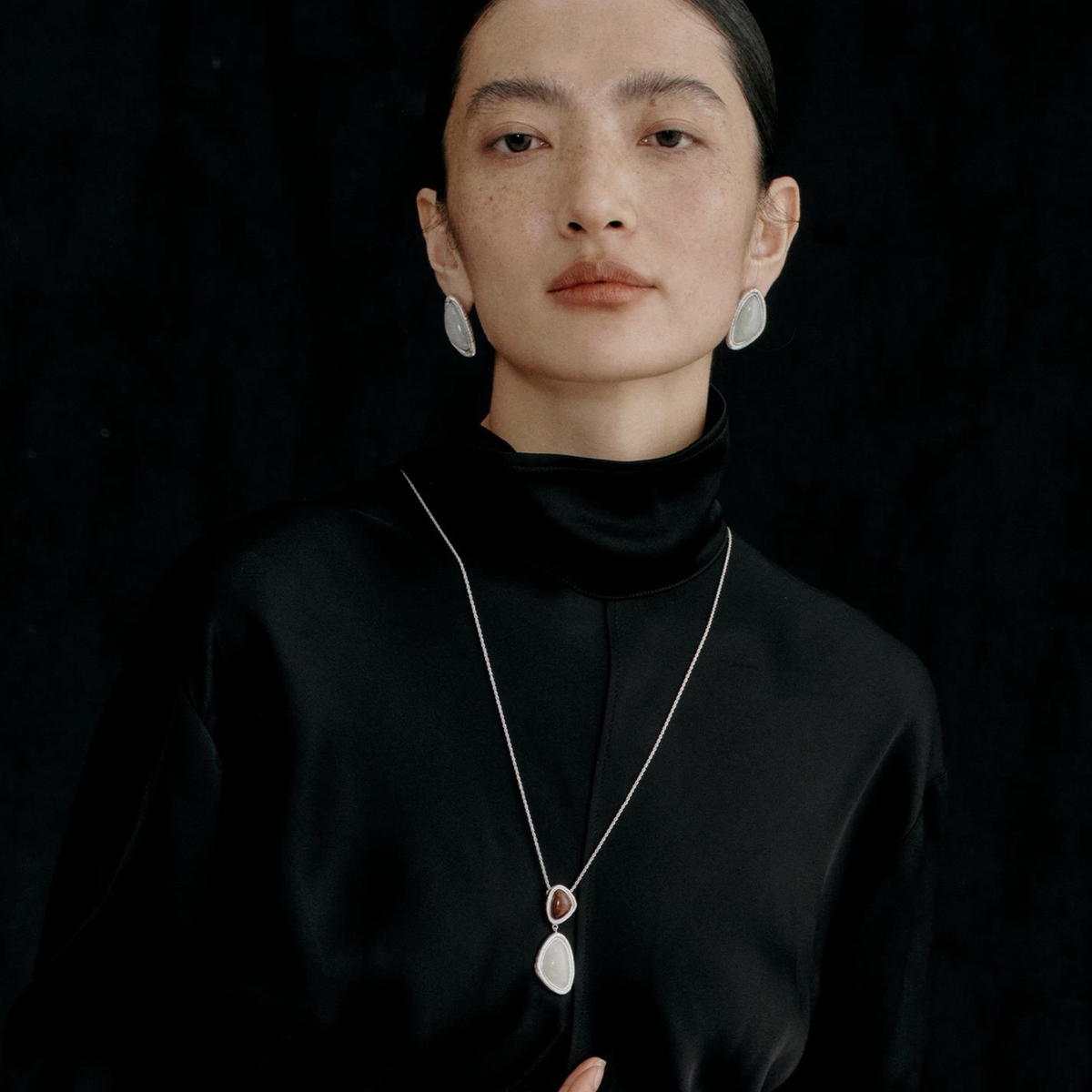 Model wearing the Silver-Tone Bound Light long natural stone necklace and triangle earrings