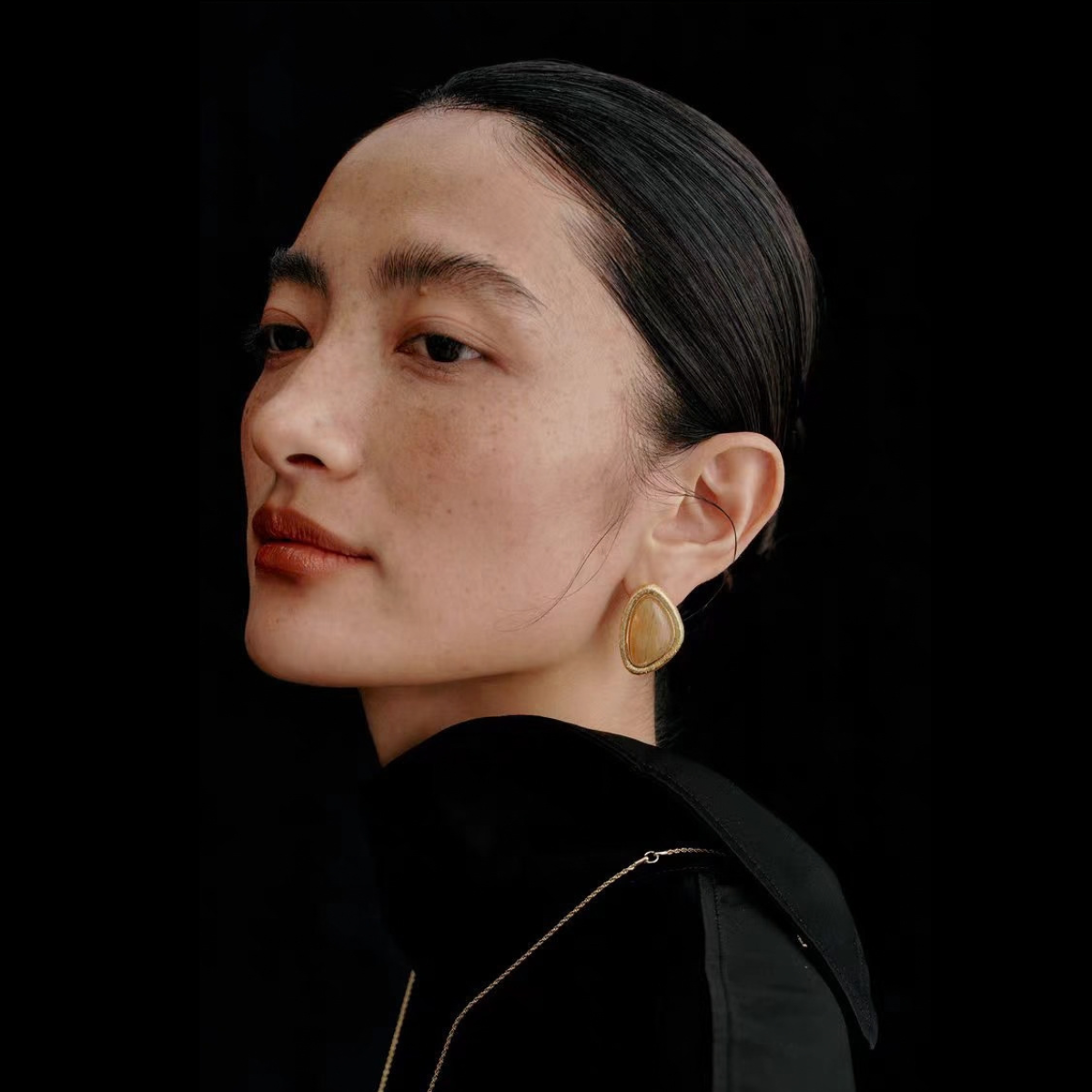 Model wearing the Bound Light natural stone triangle stud earrings in Gold-Tone finish