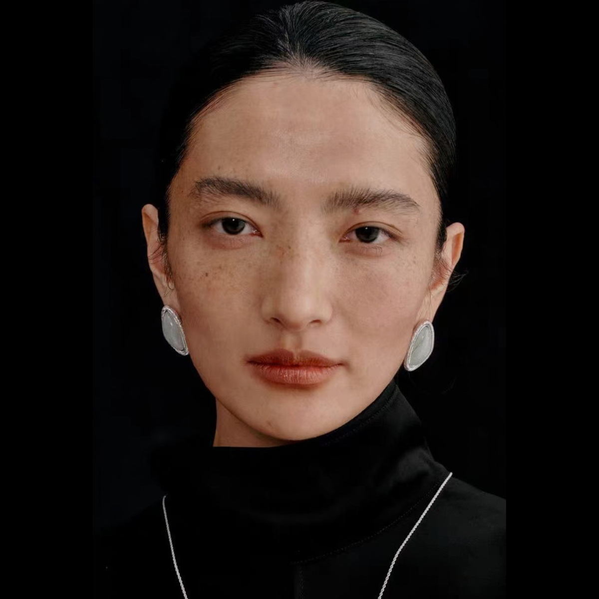 Model wearing the Bound Light natural stone triangle stud earrings in Silver-Tone finish