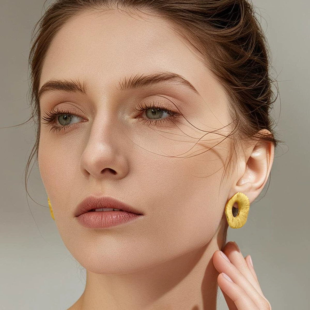 Model wearing gold-tone brushed halo open-center stud earrings