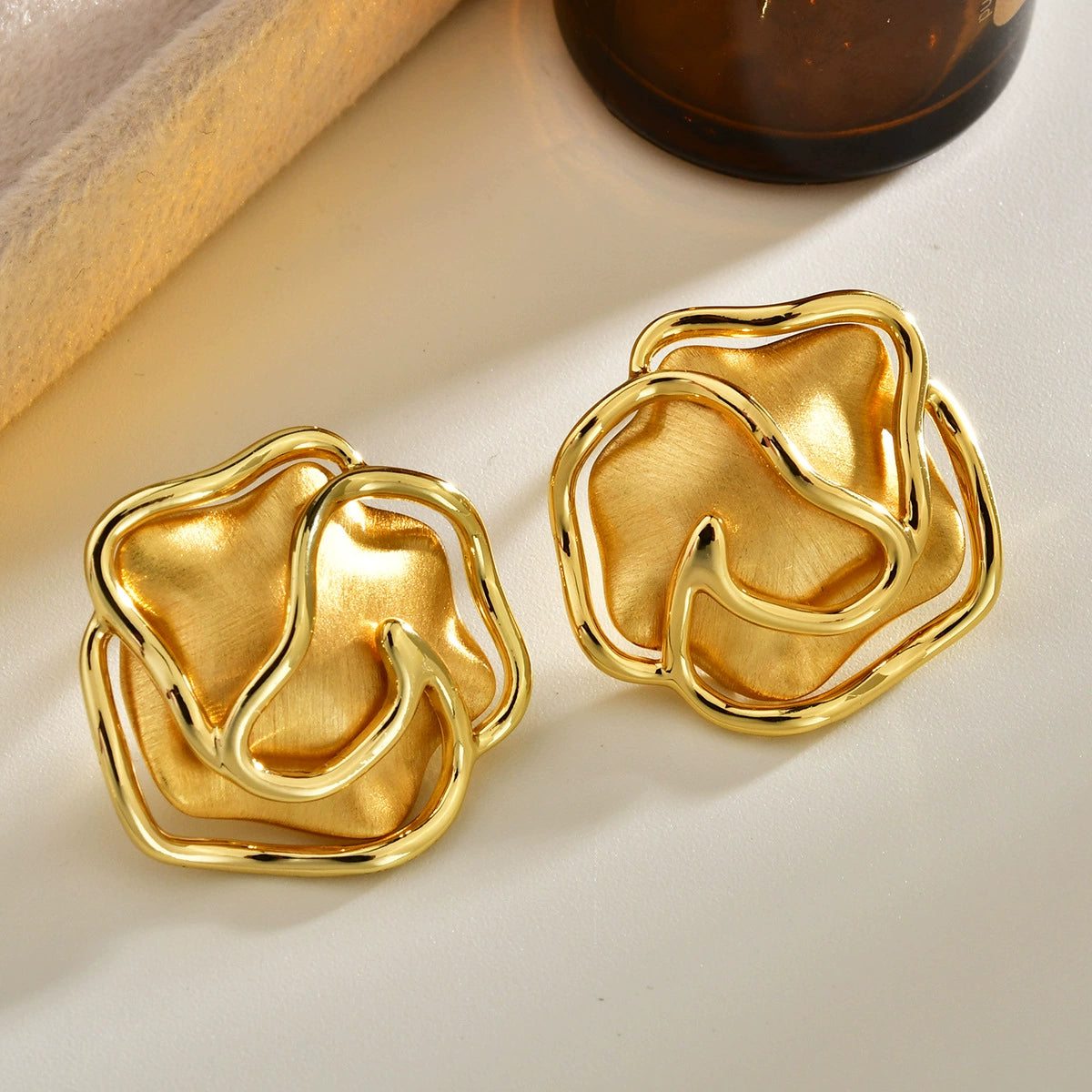 Brushed gold-tone sculptural open rose stud earrings with polished curved petal outlines