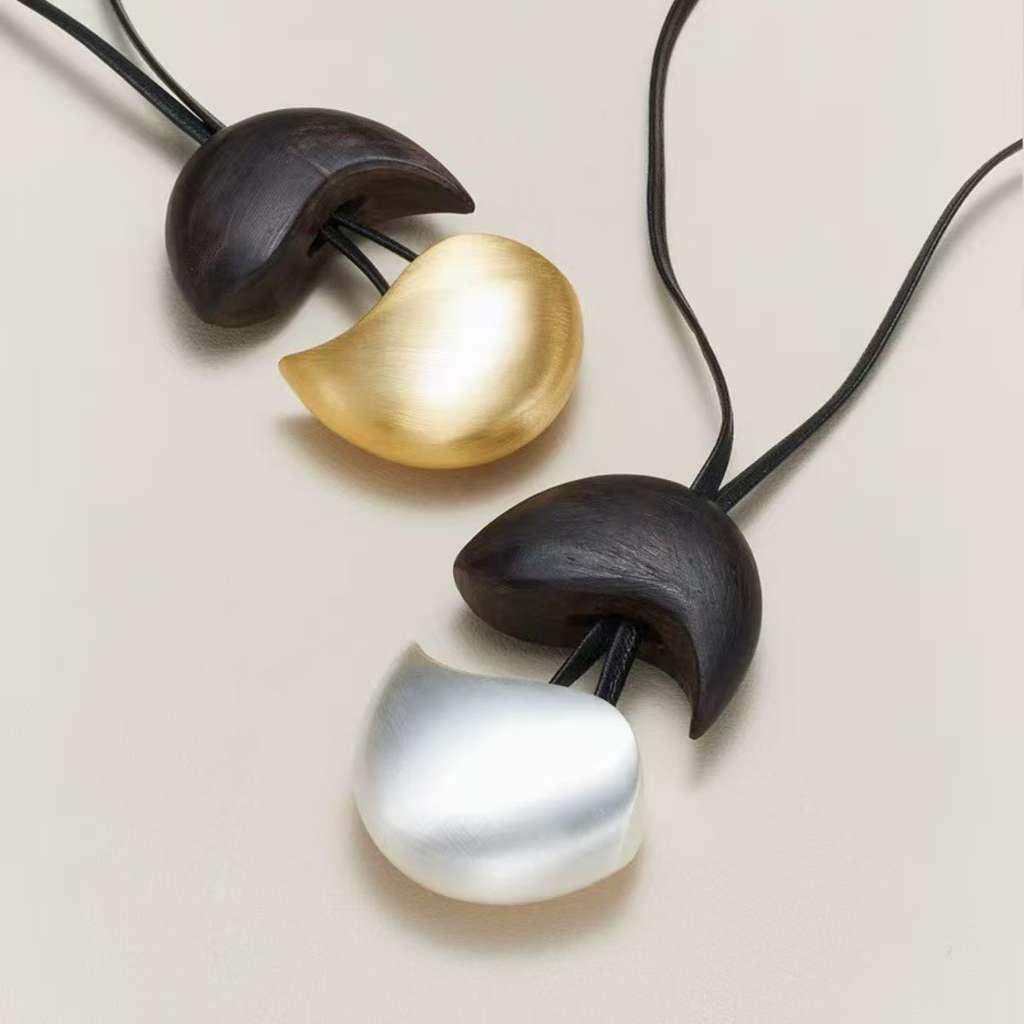 Ebony wood pendant necklace shown in gold-tone and silver-tone finishes