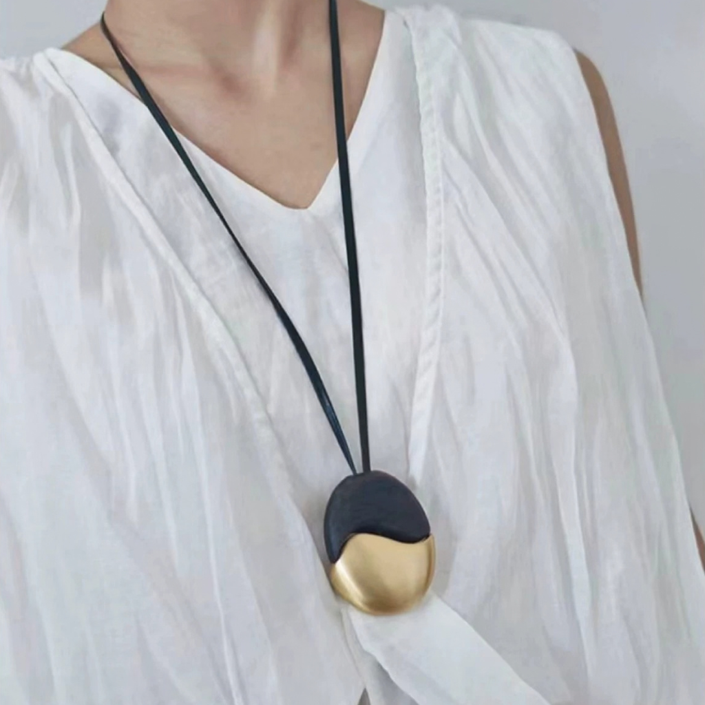 Long ebony wood and gold-tone pendant necklace on black leather cord styled on model