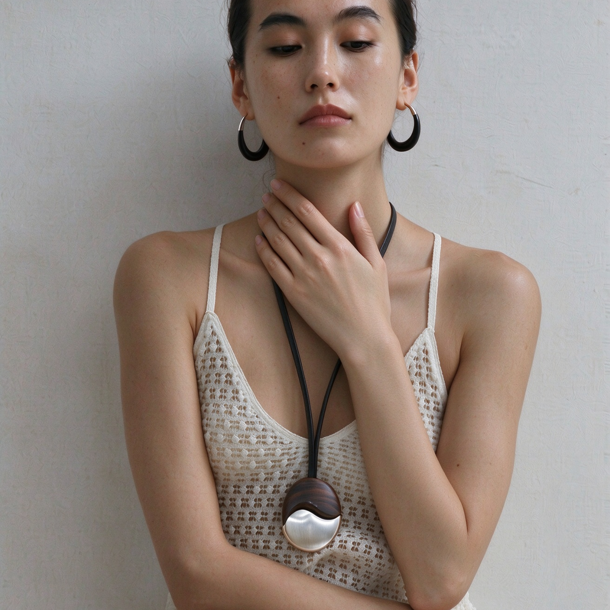 Model wearing the ebony wood pendant necklace with matching silver-tone hoop earrings