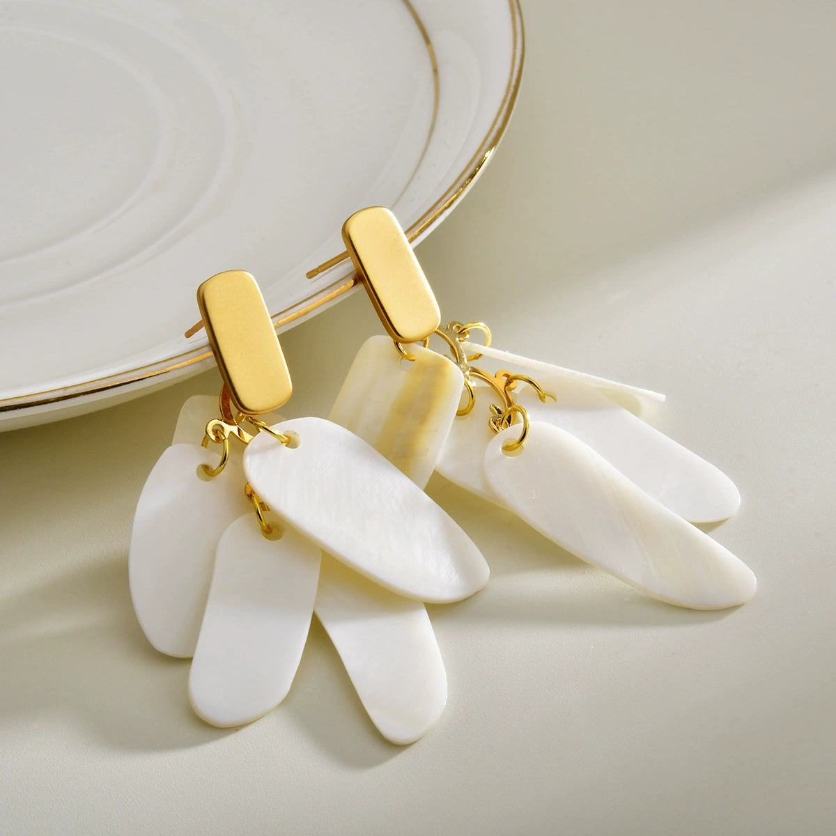 White shell layered drop earrings with polished gold-tone tops