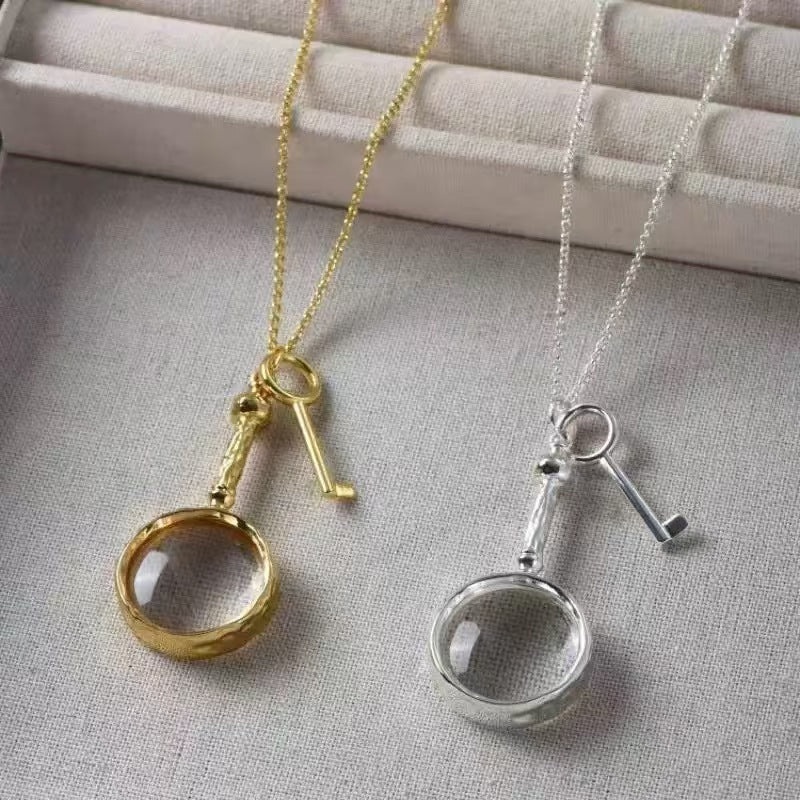 Magnifying glass and key pendant necklace details in two finishes