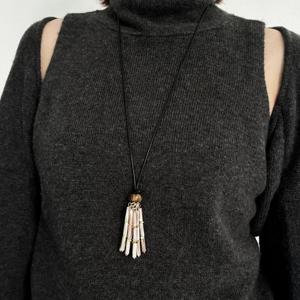 Long mother-of-pearl tassel necklace styled over black knitwear