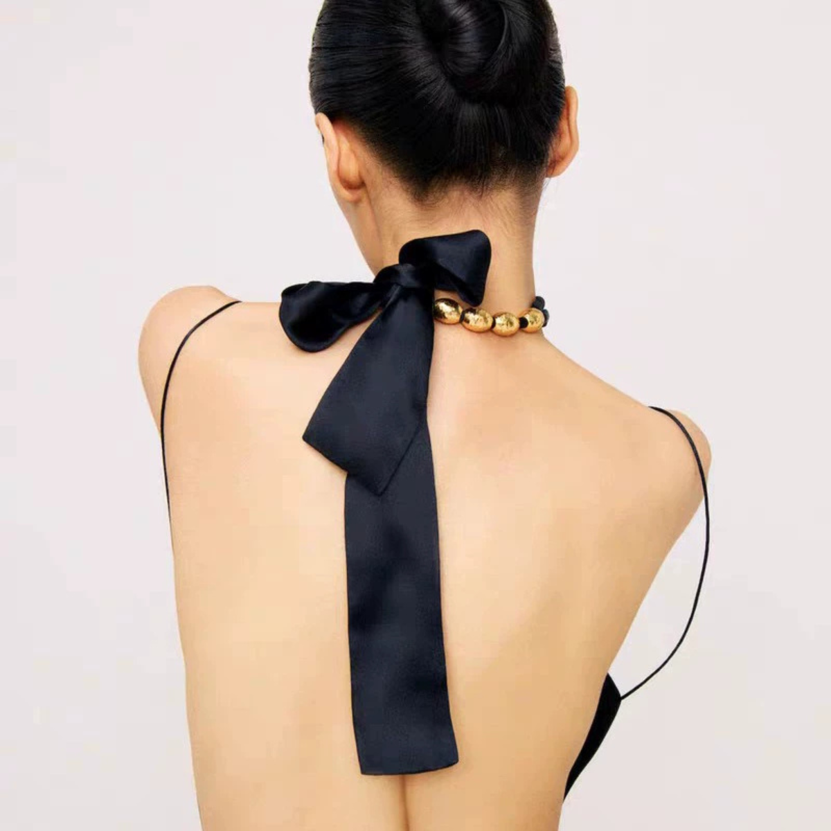 Black ribbon necklace tied in a bow with gold-tone beads