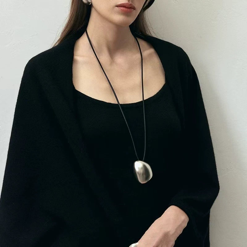 Model wearing a silver-tone sculptural pebble cord necklace with a black outfit
