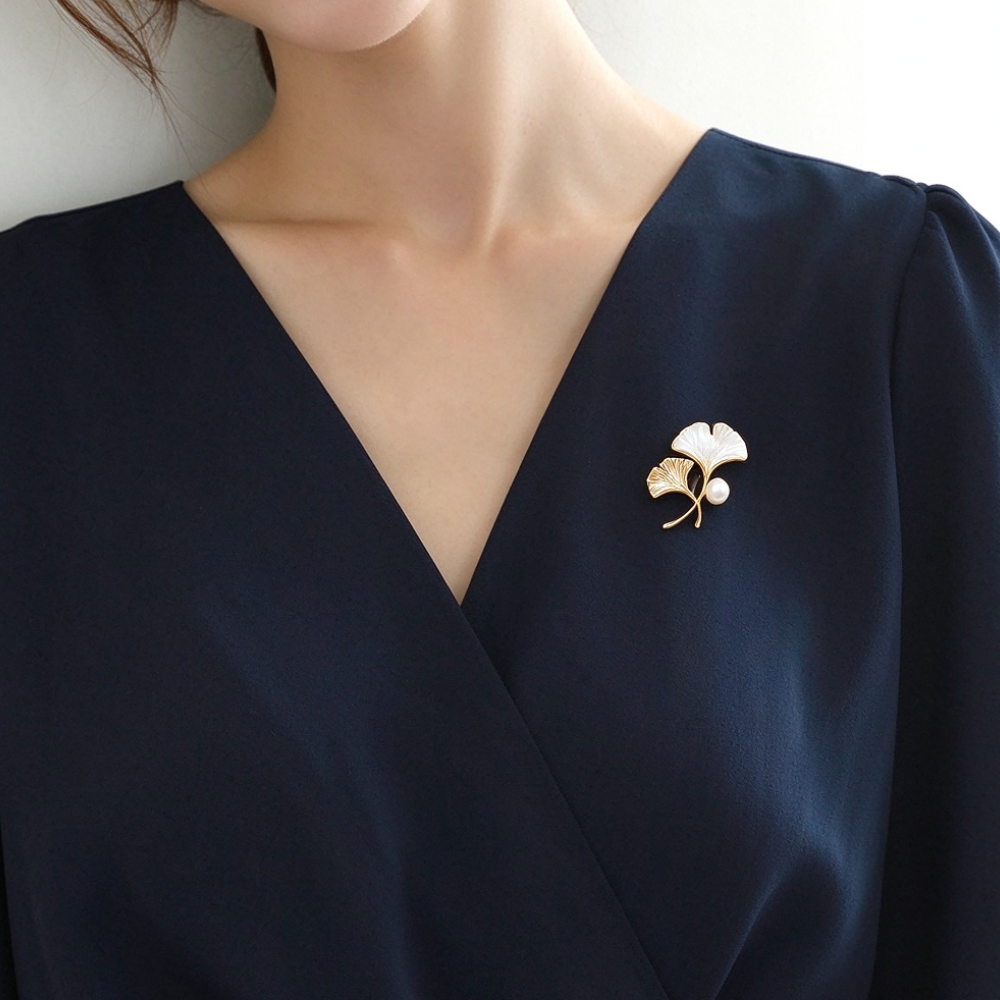Gold-tone shell ginkgo brooch styled on a navy dress