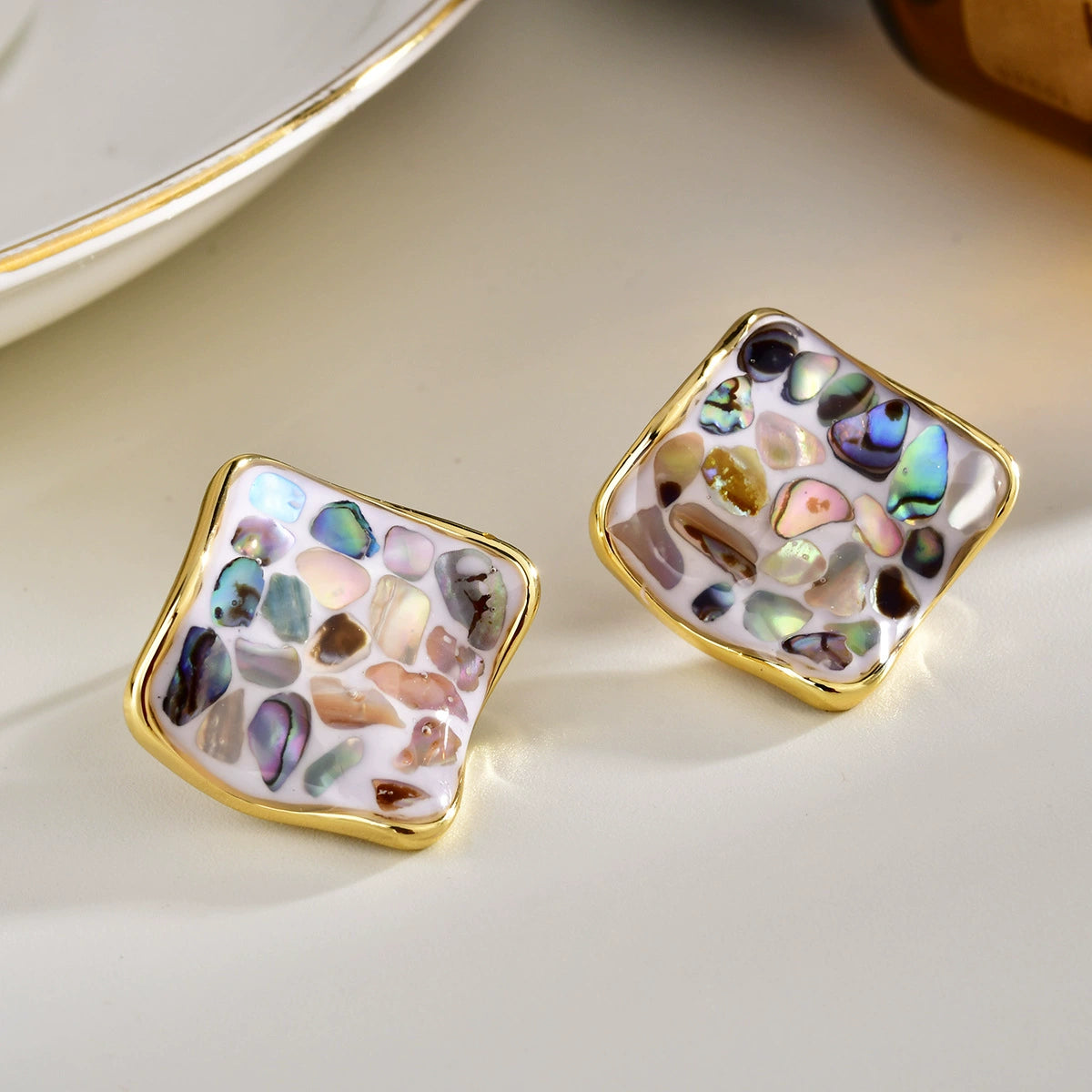 Square shell stud earrings with multicolor abalone fragments on a light background