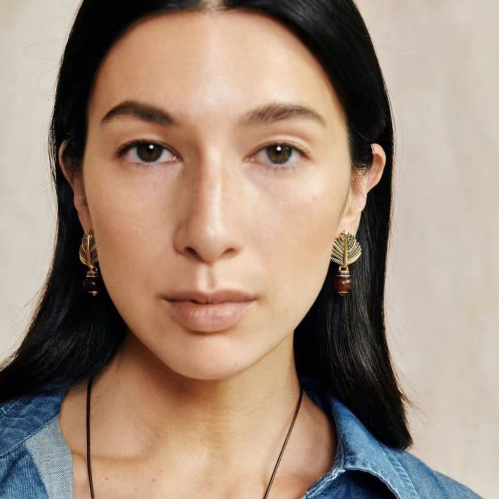 Model wearing gold-tone Swaying Palm agate stud earrings with warm caramel stone accents