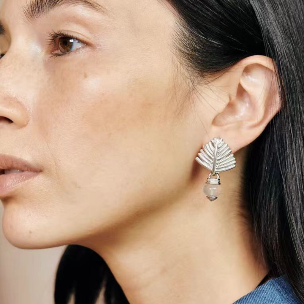Close-up of a model wearing silver-tone Swaying Palm agate stud earrings with gray stone drops