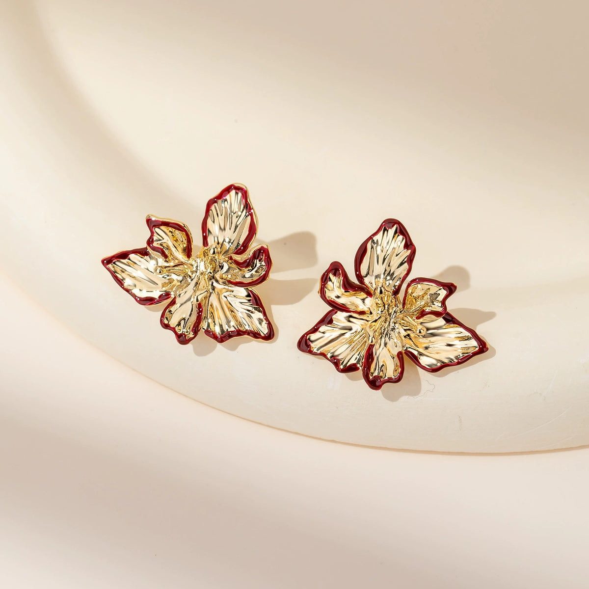Gold-tone iris flower stud earrings with textured petals and red edge details