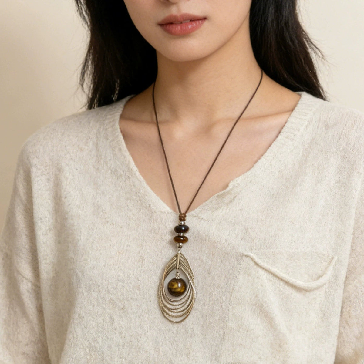 Model wearing long tiger eye pendant necklace with brown cord